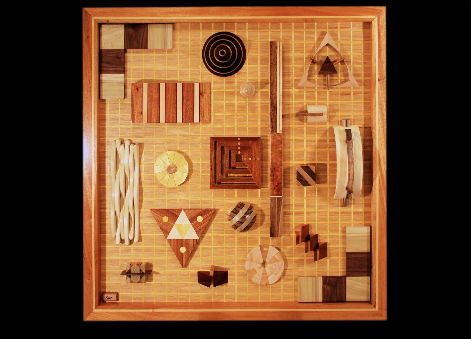 Abstract wooden assemblage with inlaid geometric shapes, stripes, and dimensional elements arranged on a grid background.